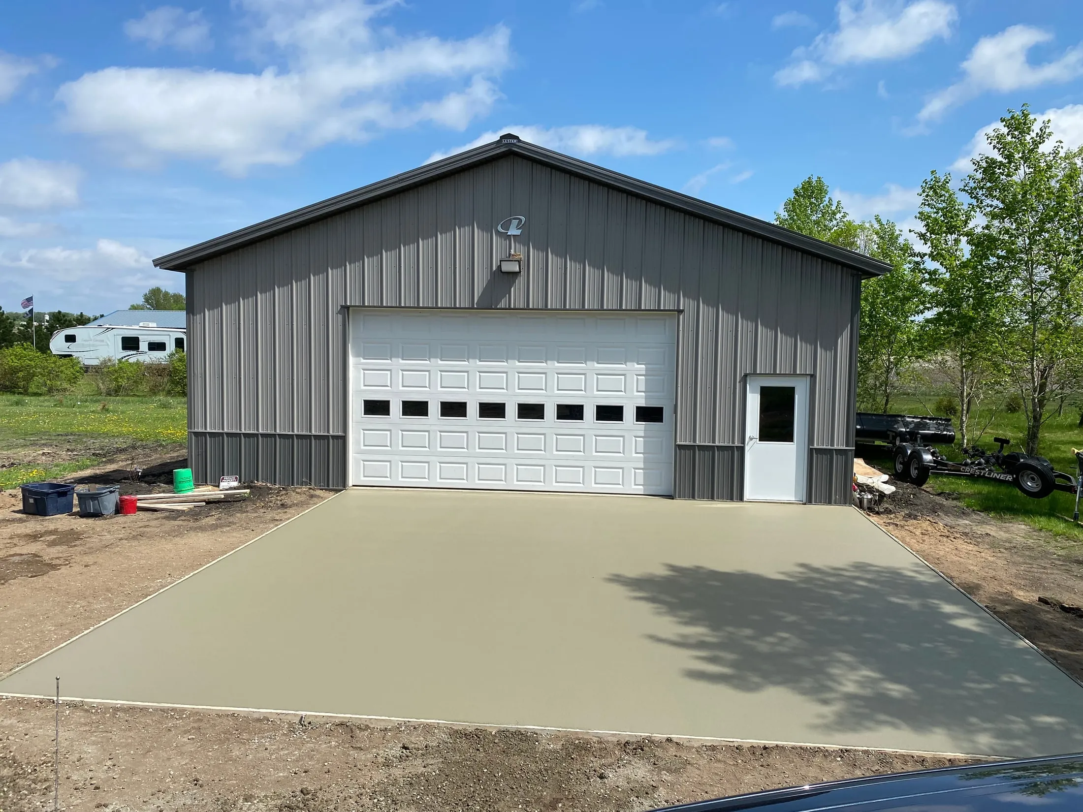 Concrete slab and approach poured at a gray metal garage.