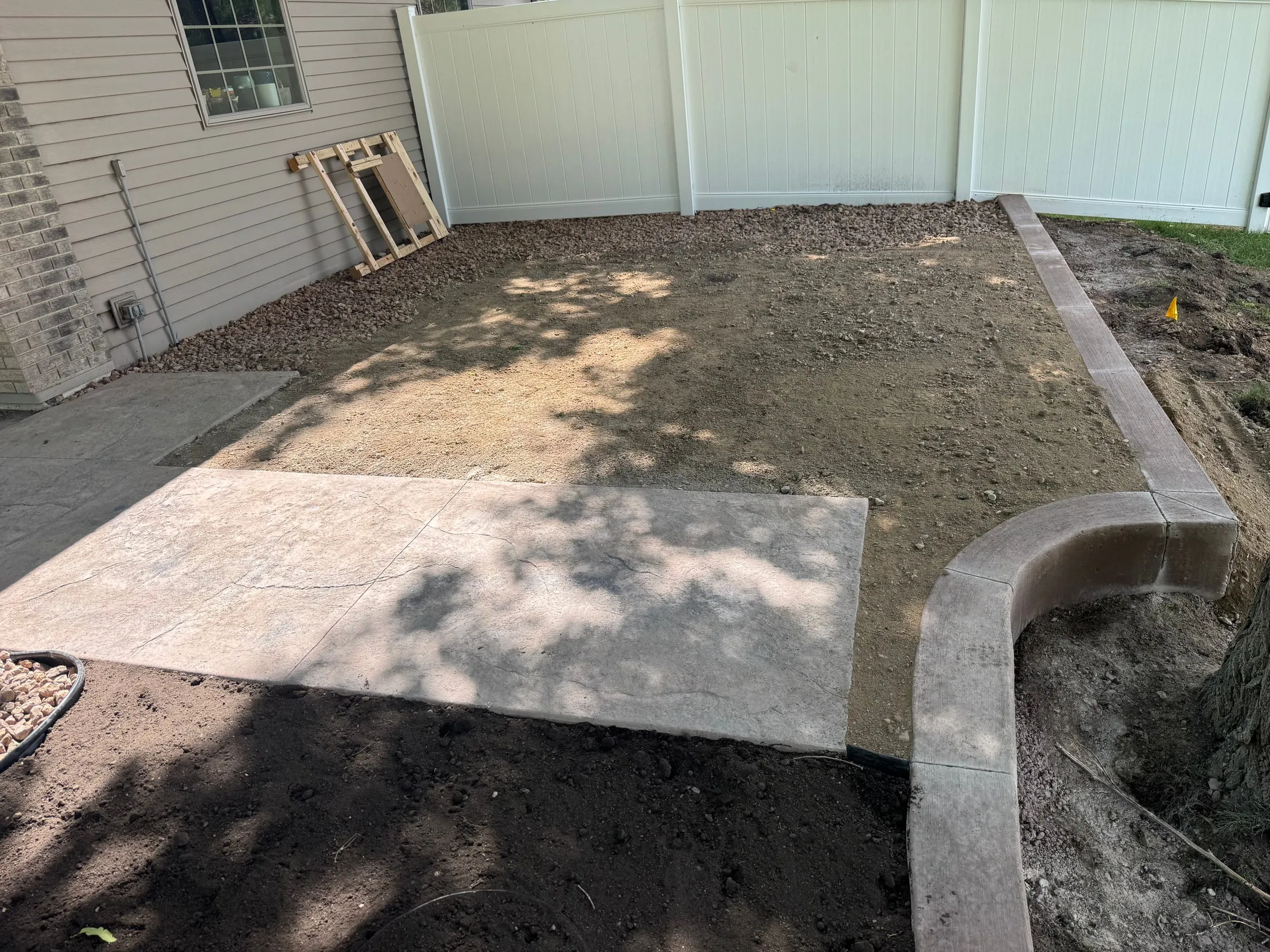 Prepared base beside an outbuilding and curved concrete edging.