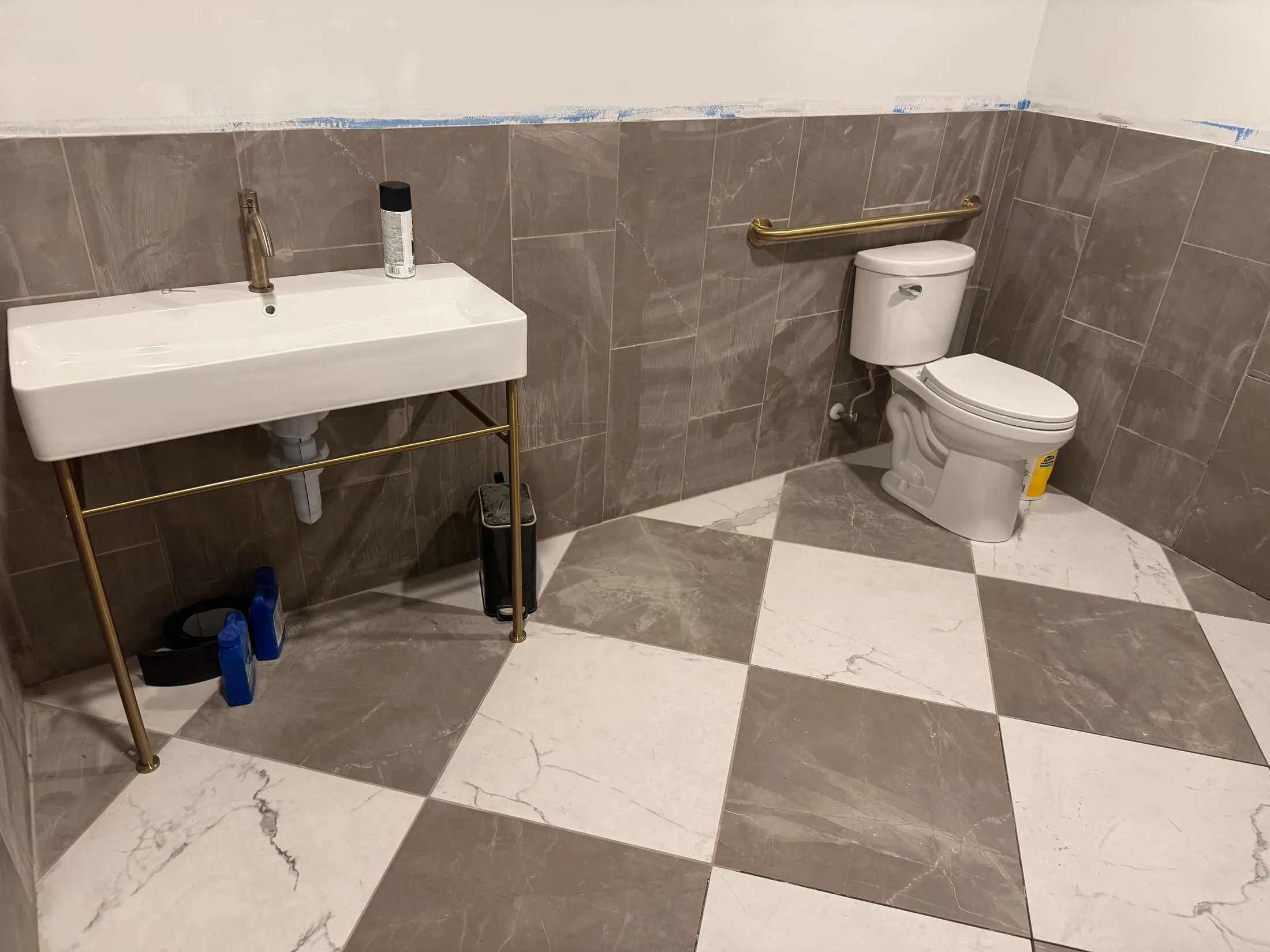 Checkerboard floor and wall tile around the sink and toilet at Tannin & Oak.
