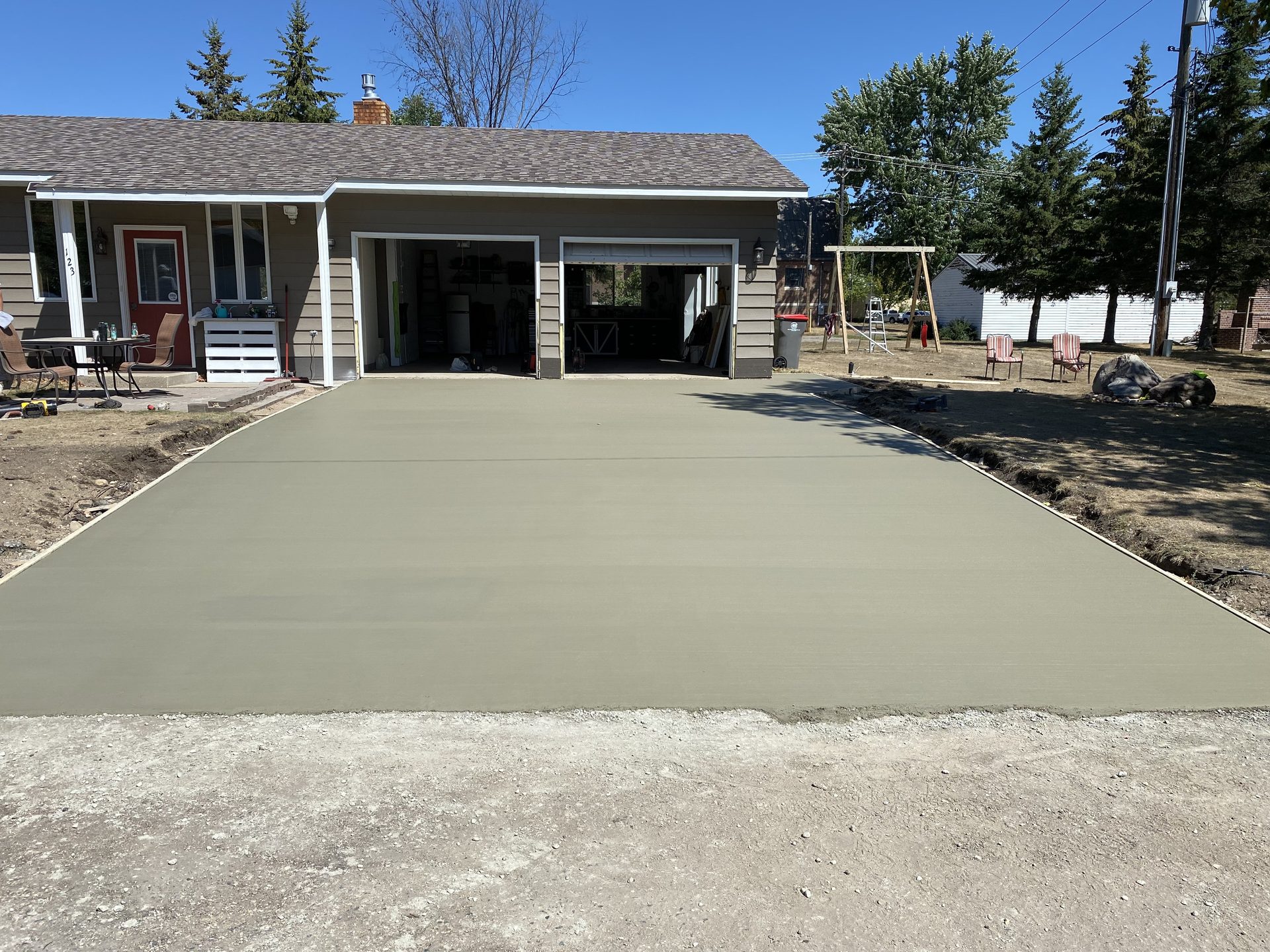 Newly installed concrete driveway in front of residential home with attached garage.