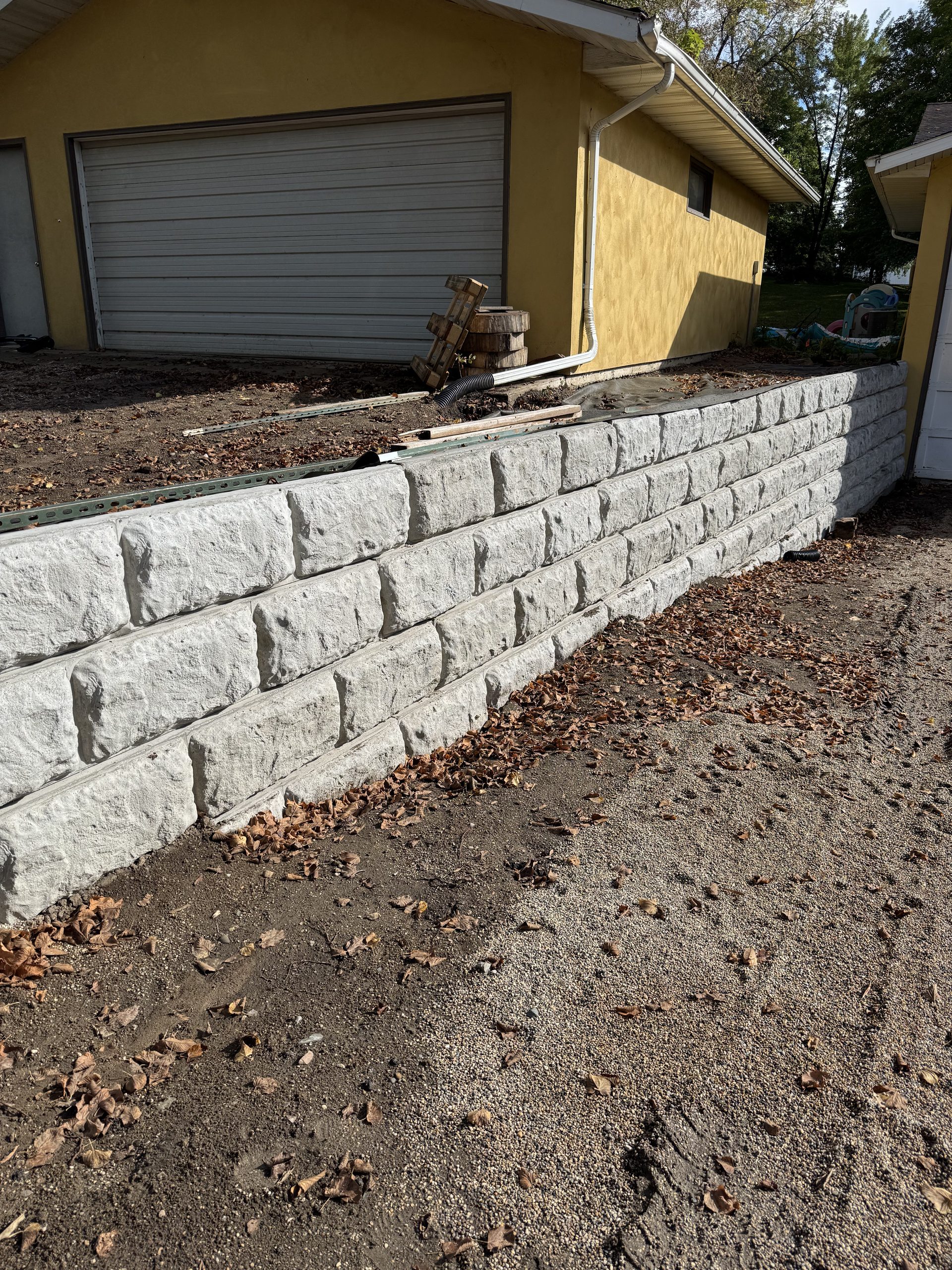 Newly installed concrete retaining wall with textured blocks, showing multi-row construction detail.