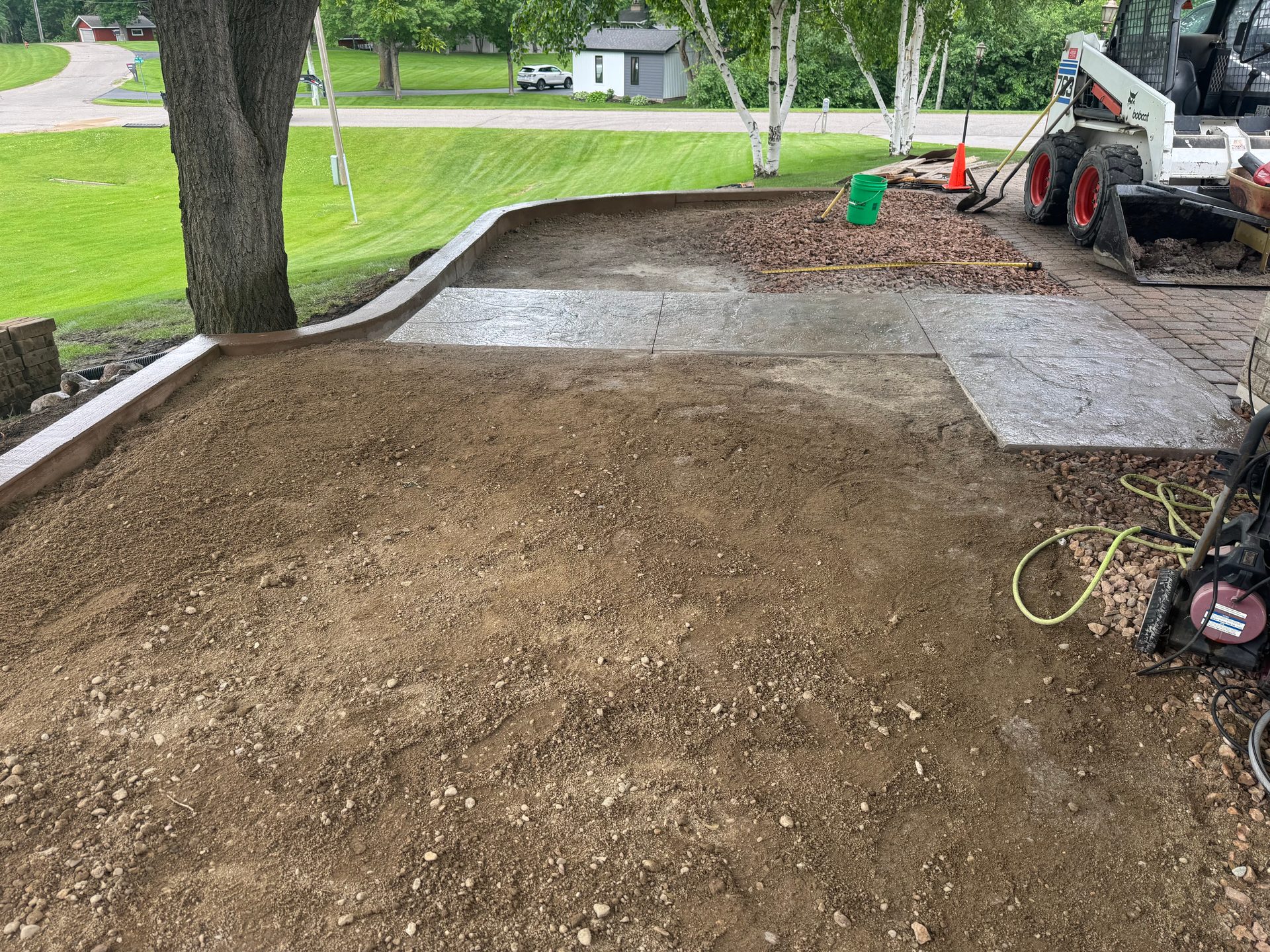 Stamped concrete patio installation in progress with skid steer and curved border edge in west-central Minnesota.
