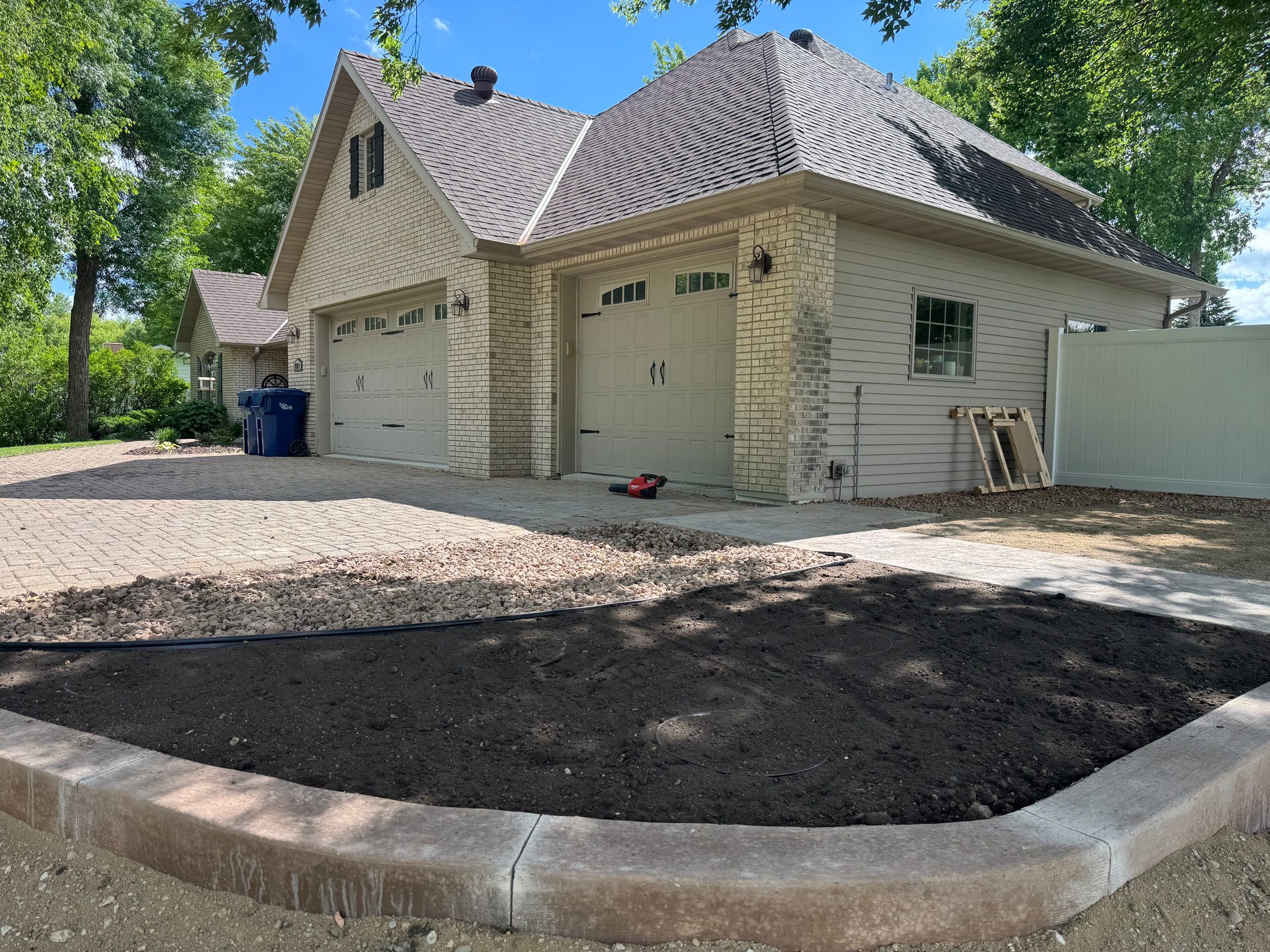 Stamped concrete patio with curved rock landscape border and attached garage at residential home in west-central Minnesota.