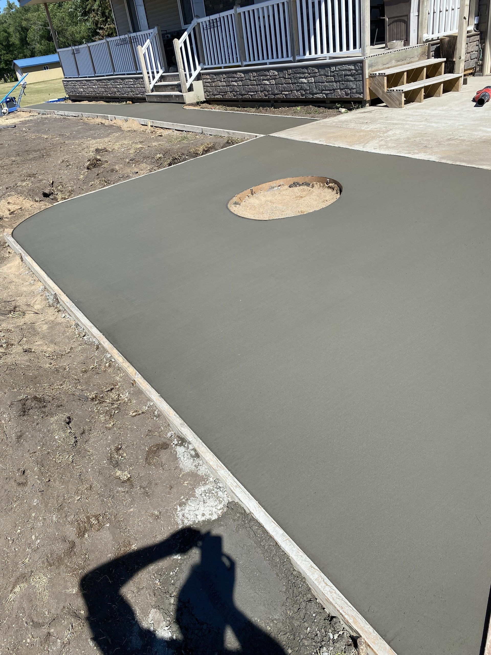 Fresh concrete patio with circular opening during construction, white edging visible along perimeter.