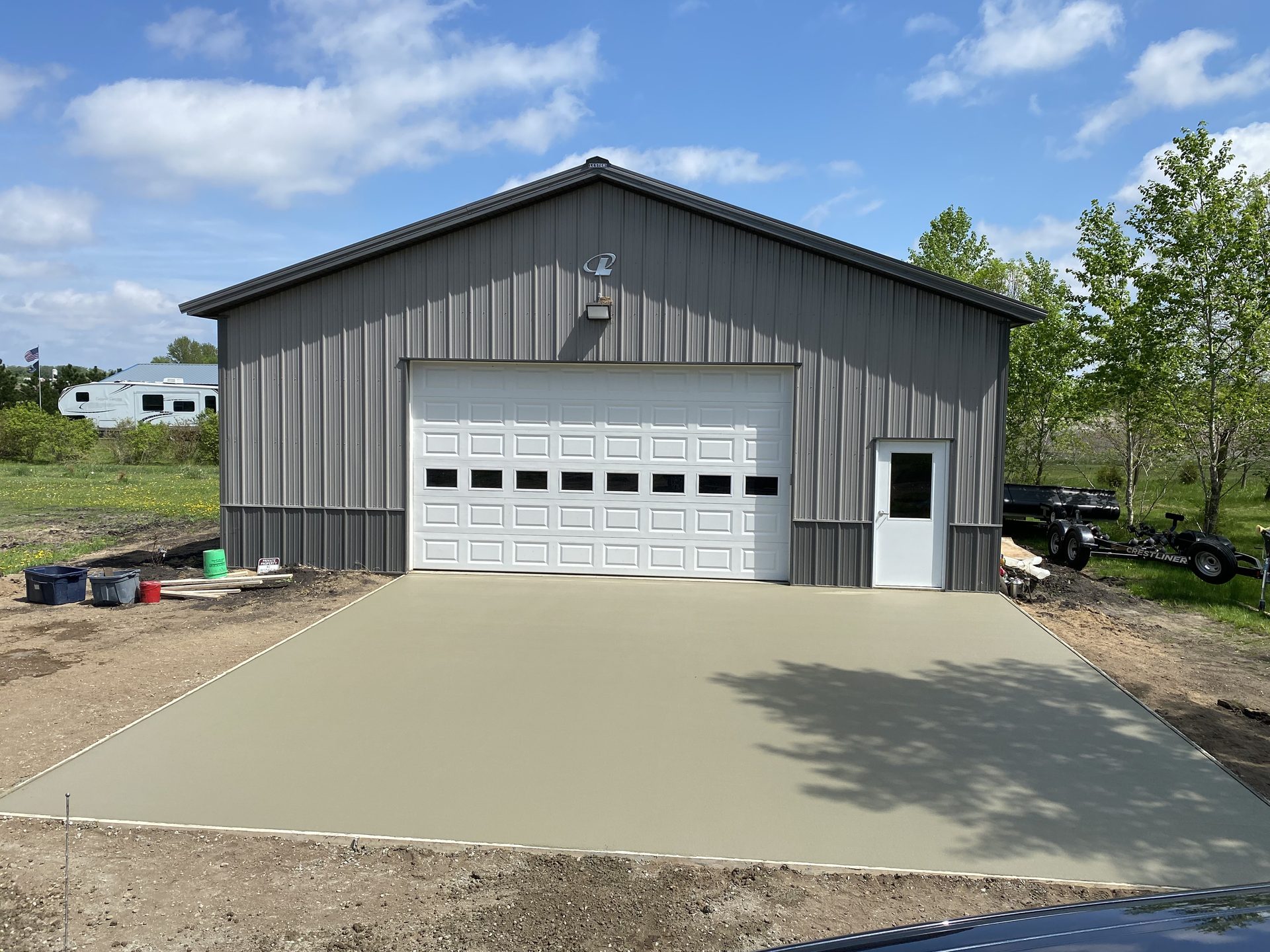 Newly completed metal-frame garage with white overhead door and concrete driveway
