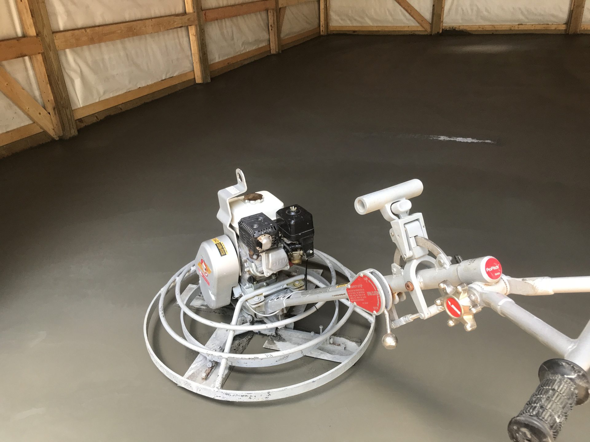 Concrete power trowel machine positioned on freshly poured concrete slab during finishing operations.