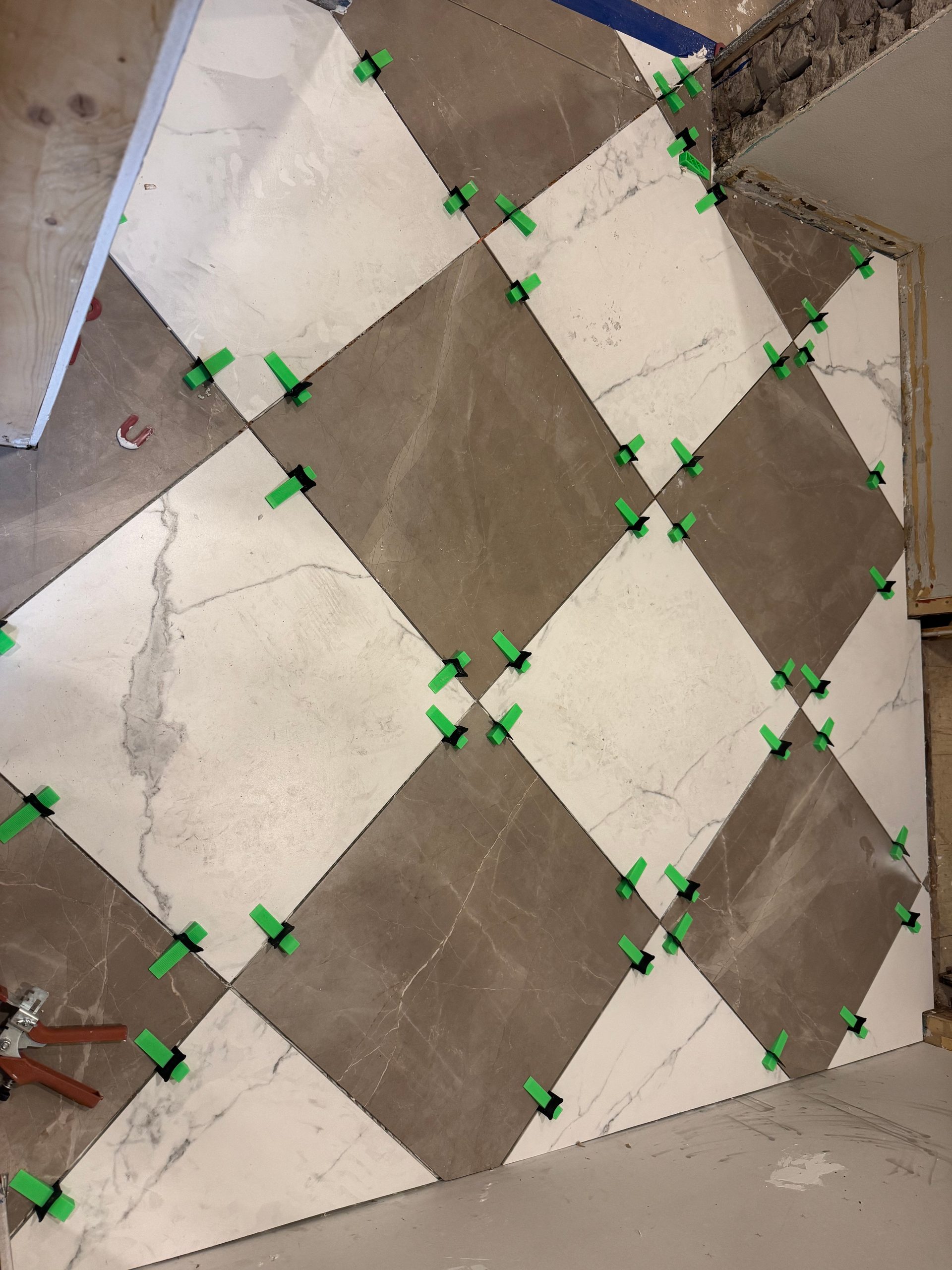 Large-format porcelain floor tile installation with diagonal checkerboard pattern and leveling clips in west-central Minnesota.